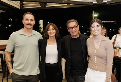 Four people with arms around each other smiling and looking into the camera